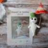 Des pages du patron de Gaspard le fantôme sont posées sur une table en bois. Sur le côté de ces pages, se trouvent une version du fantôme avec son chapeau et son parapluie. De l'autre côté, on aperçoit une guirlande lumineuse, une sorte de nuage blanc et un bout de citrouille.