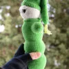 Luciole au crochet vue de profil, montrant sa forme allongée et son bonnet pointu vert, tenue dans une main, avec un arrière-plan naturel flou.