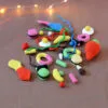 Un lot de bonbons crochetés disposés sur un fond orangé. On y trouve des bananes, des œufs au plat, des frites, des réglisses, un grosse fraise, et d'autres encore. À l'arrière-plan, dans le coin supérieur gauche se trouve une guirlande lumineuse.