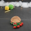 sur un fond gris foncé, il y a un panier crocheté en topaze, des fruits rouges miniatures sont disposés devant lui : fraises, cerises et baies variées (framboises, mûres,...). À l'arrière plan, sur la gauche il y a 2 pelotes jaune et verte et un crochet. En fond est disposé un nuage de ouate et une guirlande lumineuse.