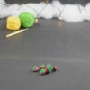 sur un fond gris foncé sont disposés des baies miniatures crochetés : framboises, mûres,... À l'arrière plan, sur la gauche il y a 2 pelotes jaune et verte et un crochet. En fond est disposé un nuage de ouate et une guirlande lumineuse.