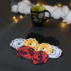 Huit sous-verres ronds crochetés sont posés sur un fond gris sombre. Ils sont de différentes couleurs (dégradé parme et lilas, dégradé orange et jaune, dégradé violet et aubergine et uni noir. En fond il y a une tasse noire à l'intérieur vert clair et des guirlandes lumineuses sont disposées sur du rembourrage blanc façon nuages.