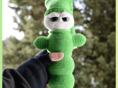 Luciole au crochet, de couleur verte avec un visage clair et de grands yeux. Elle porte un bonnet et est tenue dans une main, photographiée en extérieur devant un arrière-plan naturel flou.