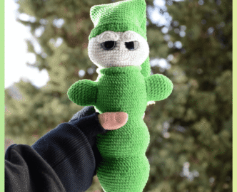 Luciole au crochet, de couleur verte avec un visage clair et de grands yeux. Elle porte un bonnet et est tenue dans une main, photographiée en extérieur devant un arrière-plan naturel flou.